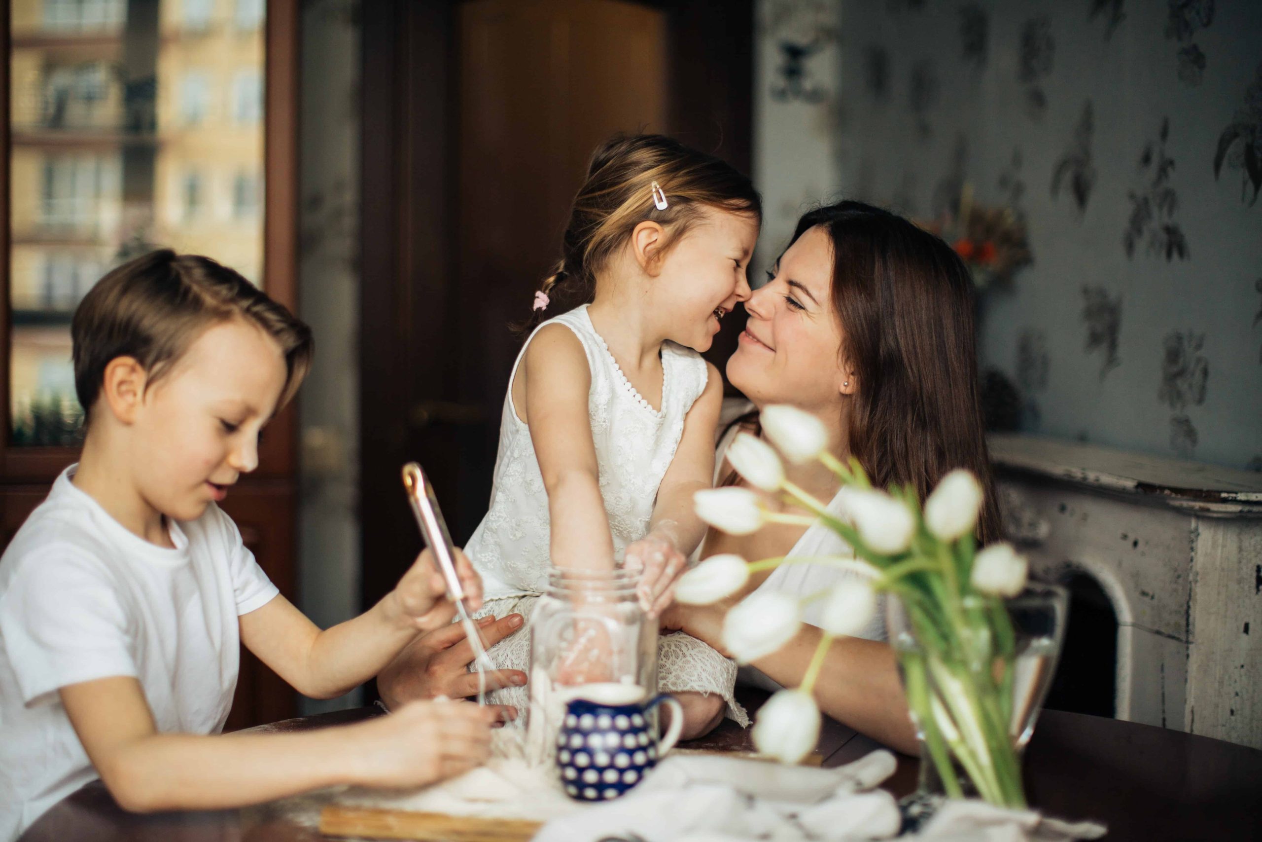 Two kids sitting at the table with their mother